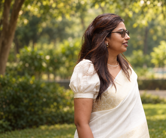 ZEEVAAH founder in side profile wearing a white-and-gold saree and gold earrings